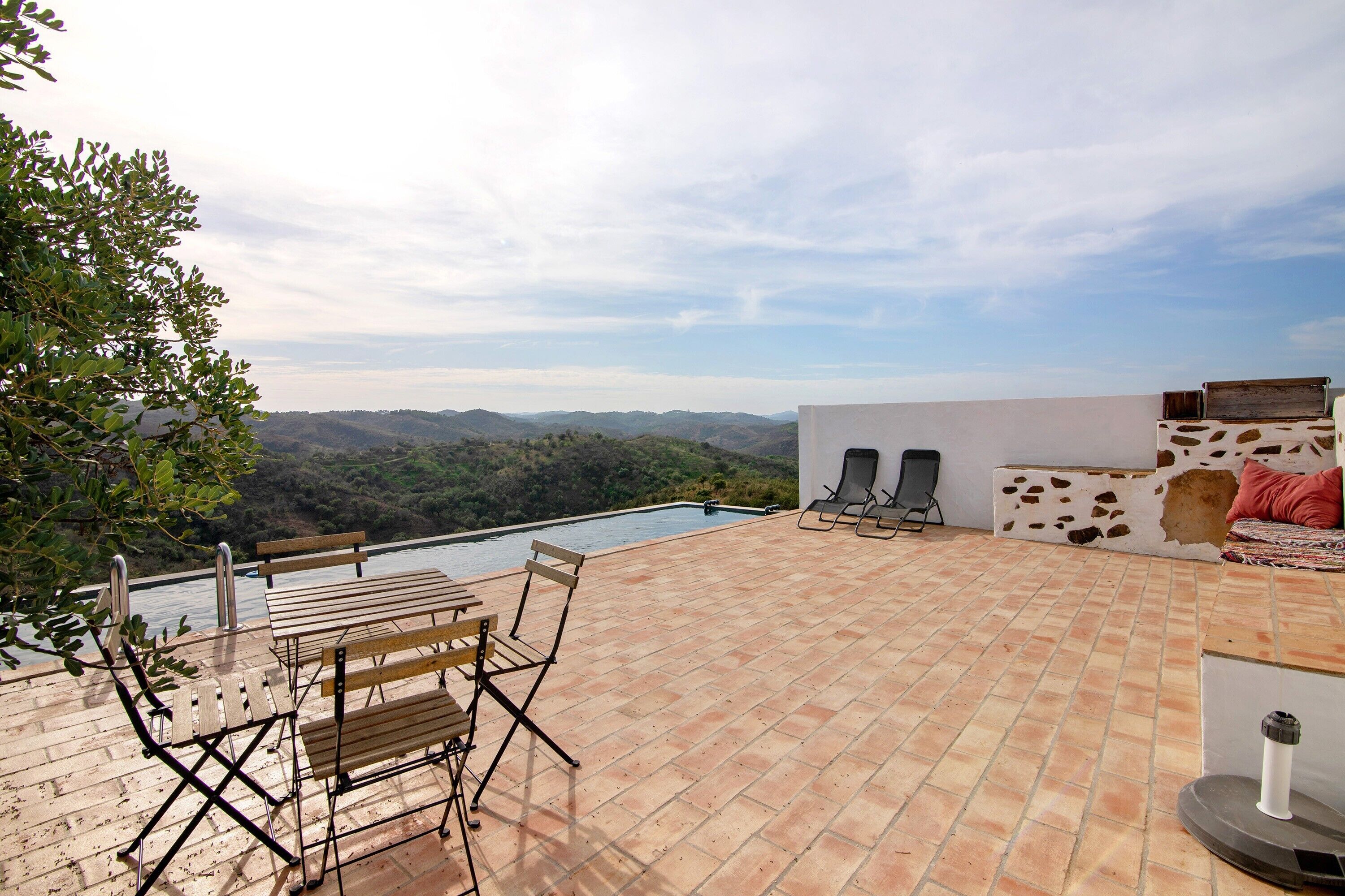 Un patio al aire libre con piscina, asientos y vistas panorámicas.