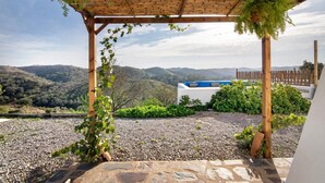 Spazio esterno coperto con vista sulle colline, una pergola in legno e un sentiero in pietra.