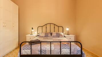 Um quarto com uma cama, mesas de cabeceira e um guarda-roupa.