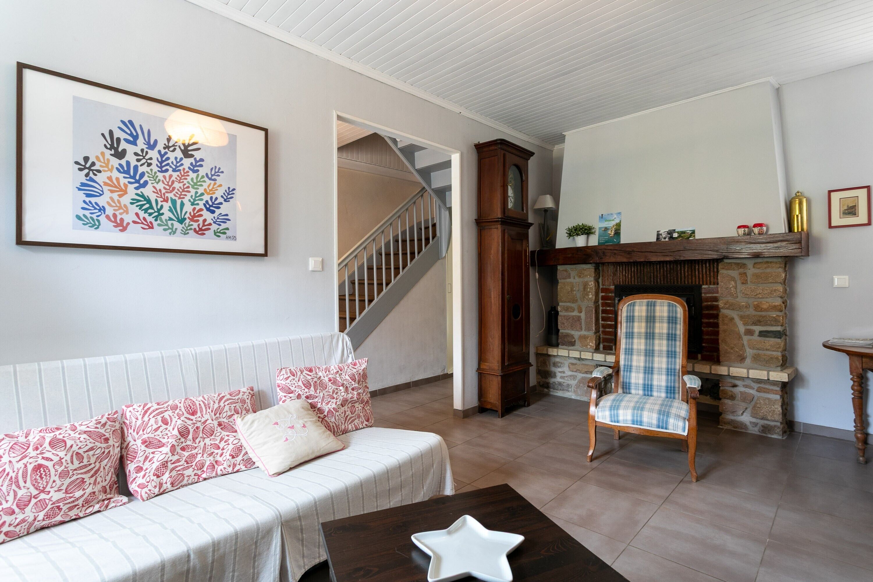 A living room with a sofa, a chair, a fireplace, and a staircase.