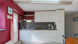 A compact kitchen with white cabinets, a built-in microwave, and a coffee maker.