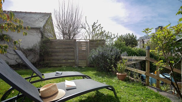 A garden with a wooden fence, a chair, a hat, and a book.