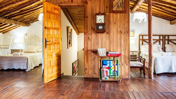 Una habitación rústica de madera con una cama, un armario de madera lleno de libros y un reloj de pared.