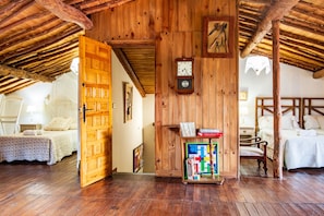 A rustic wooden room with a bed, a wooden cabinet with books, and a wall clock.