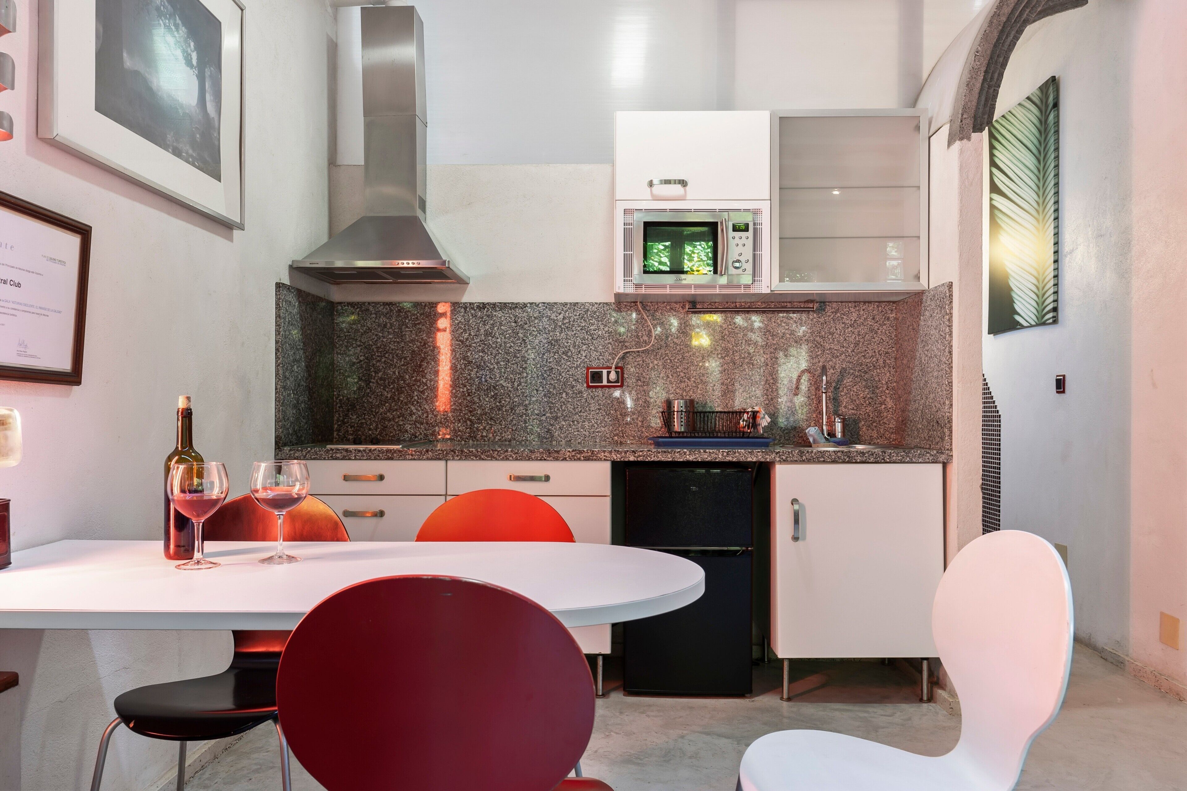 Une cuisine moderne dotée de plans de travail en granit, d’un four à micro-ondes et d’un four encastré. On y trouve une table à manger avec des chaises, une bouteille de vin et des verres.