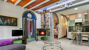 Een moderne woonkamer met een open haard, een televisie en een eethoek met stoelen.