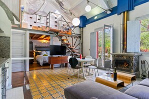 A spacious living area with a fireplace, a staircase, and a television.