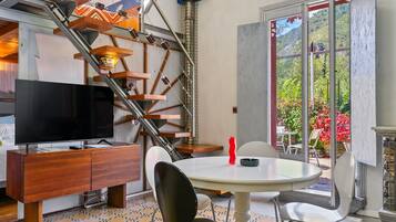 Un interior moderno con una escalera, un televisor de pantalla plana, una mesa de comedor y sillas.