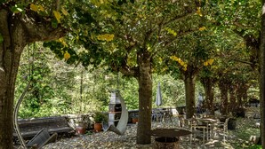 A rustic outdoor seating area with benches, tables, and a grill.