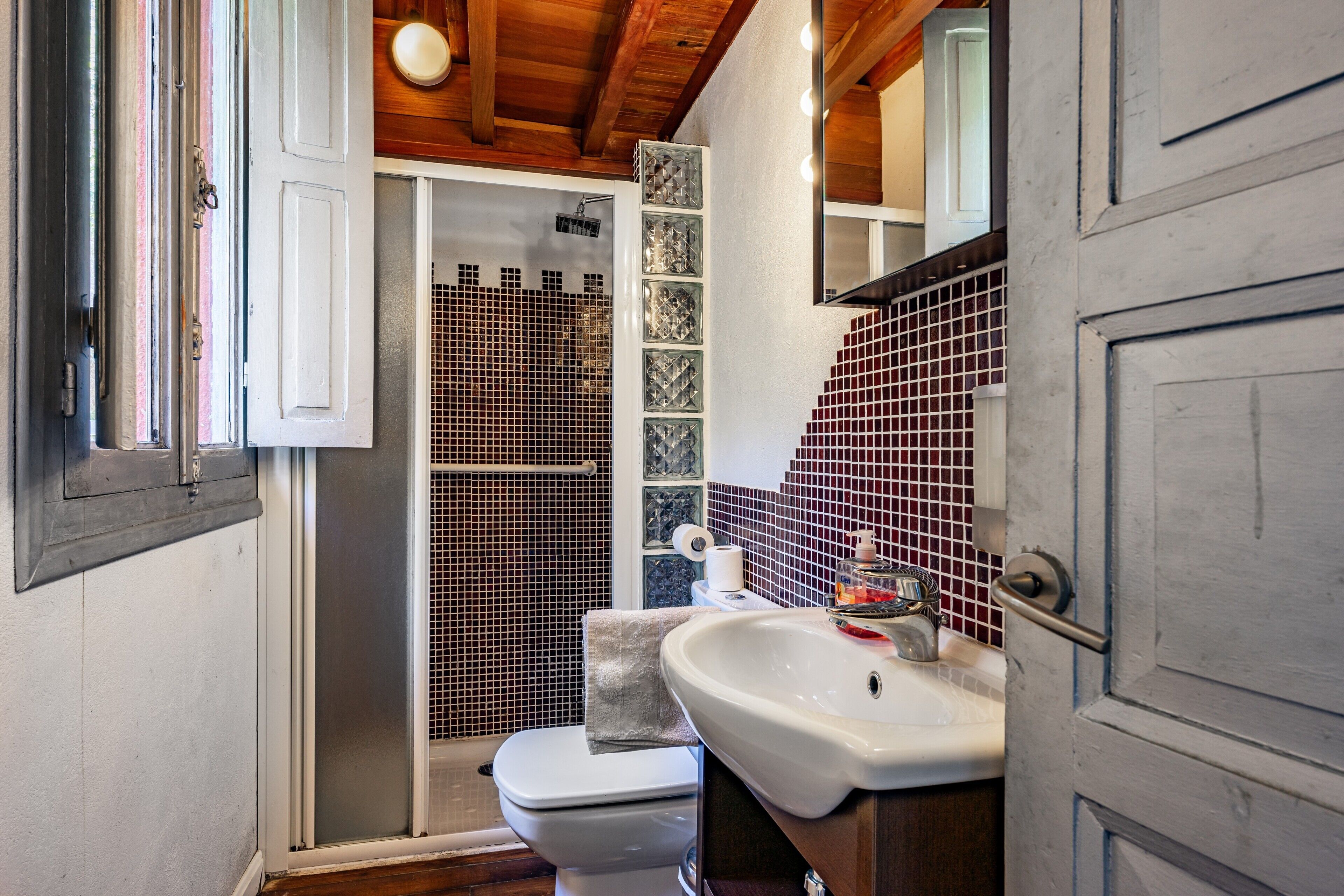 Un baño con ducha, inodoro, lavamanos y espejo.