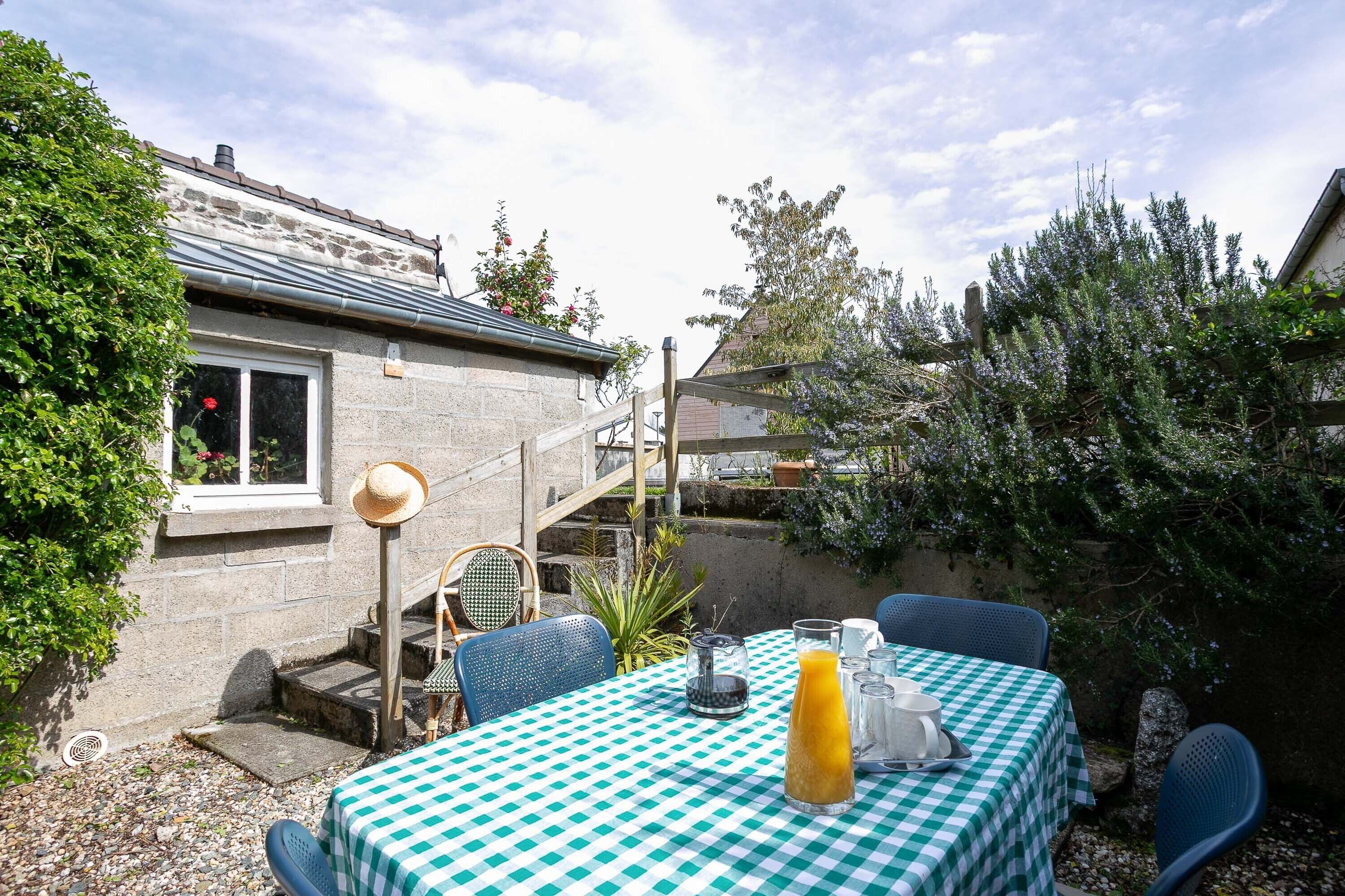 A patio with a checkered tablecloth, outdoor seating, and a stone building in the background.