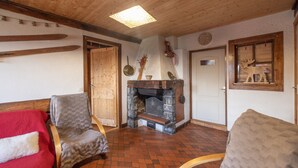 A cozy room with a fireplace, wooden beams, and skis on the wall. - Apartment 'La Charbonnière' with Mountain View, Private Garden and Wi-Fi (Cordon)