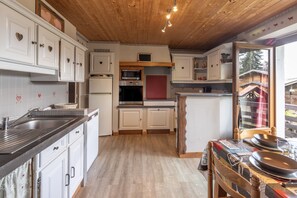 Eine Küche mit weißen Schränken, einer Holzbalkendecke und einem Essbereich mit gedecktem Tisch für zwei Personen.
