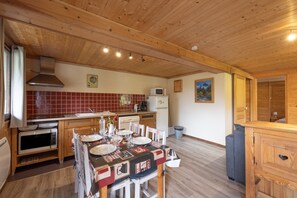 Una cocina con paneles de madera y una mesa de comedor preparada para cuatro personas, un microondas, una estufa y un refrigerador.