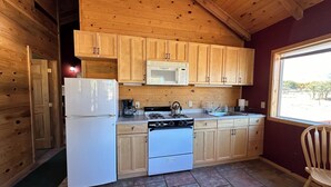 Una cocina compacta con armarios de madera, un refrigerador blanco, una estufa y un microondas.