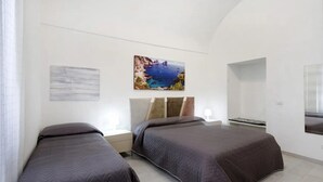 A bedroom with two beds, a nightstand, a wall-mounted TV, and a painting of a coastal scene. - Apartment 'Penisola Apartments' with Shared Terrace, Wi-Fi and Air Conditioning (Vico Equense)