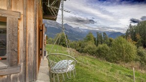 A wooden cabin with a swing chair overlooking a mountainous landscape. - Chalet 'Petit Cosy' with Mountain View, Wi-Fi and Air Conditioning (Combloux)