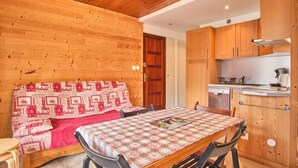 A wooden interior with a bed, a table, and a kitchen area. - Chez M & M Apartment – Balcony & Private Parking in Résidence Shrischss (Les Deux-Alpes)