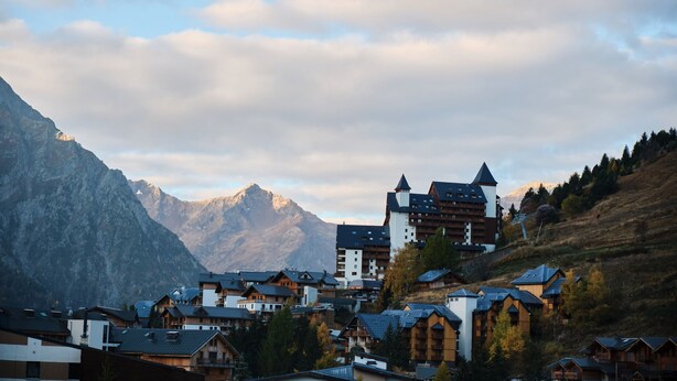 A mountain town with traditional wooden buildings, a prominent hotel with a tower, and a backdrop of mountains. - Apartment 'Meijotel' with Mountain View and Balcony (Les Deux-Alpes)