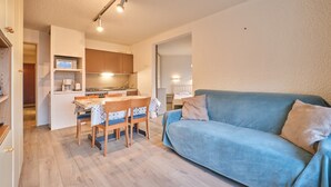 A compact living space with a kitchenette, a dining area, and a sofa. - Apartment 'Meijotel' with Mountain View and Balcony (Les Deux-Alpes)