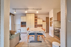 Uma cozinha compacta com mesa de jantar, cadeiras, sofá e forno embutido.