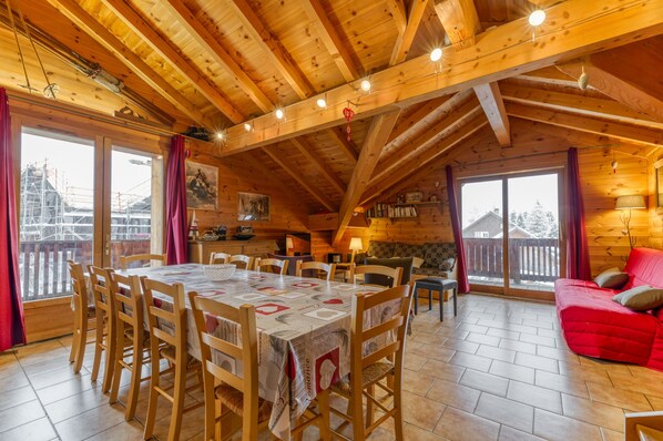 A wooden cabin with a dining area, a sofa, and a kitchen.