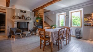 A dining area with a table, chairs, a fireplace, and a staircase. - Cottage for Four in Nature – Préalpes d'Azur Regional Natural Park (Valderoure)
