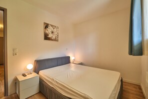 Una camera da letto con un letto, lampade da comodino, un comodino, un'opera d'arte appesa al muro e una porta.