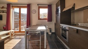 A modern kitchen with a dining area, large windows, and a view of buildings.
