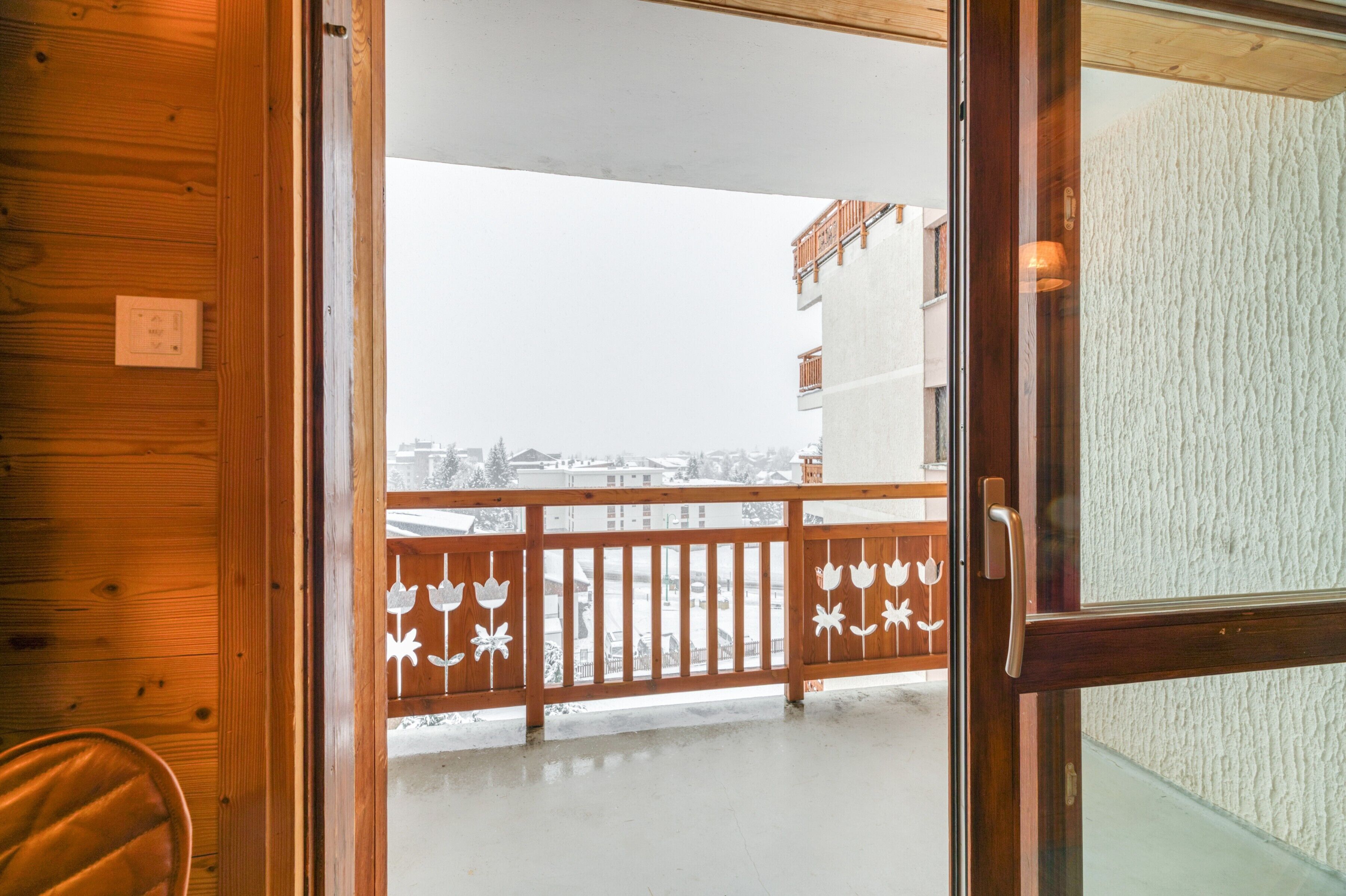 A wooden interior with a glass door leading to a balcony with a metal railing.