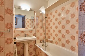 A bathroom with a sink, mirror, and shower.
