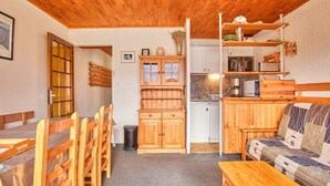 A wooden interior with a dining area, a sofa, and a kitchen.