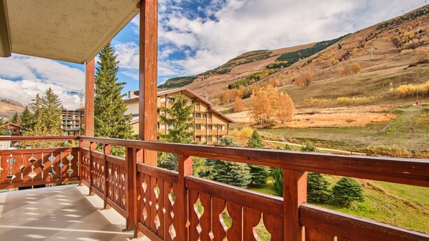 A balcony with a wooden railing overlooking a mountainous landscape.