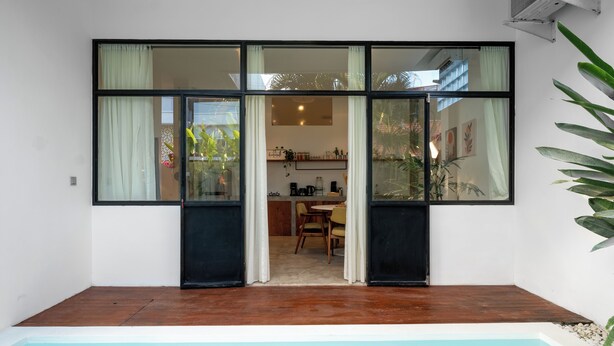 A modern house with a pool, large windows, and a dining area visible through the glass doors. - Berawa Factory Lofts (Canggu)