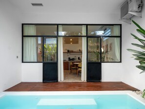 Ein modernes Haus mit Pool, großen Fenstern und einem Essbereich, der durch Glastüren sichtbar ist.