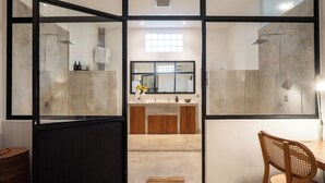 A modern bathroom with a glass partition, a wooden vanity, and a mirror. - Berawa Factory Lofts (Canggu)