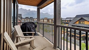 Ein Balkon mit Holzboden, einem Grill und einem Stuhl.