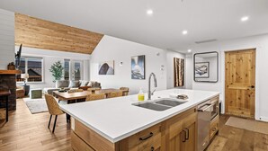 Eine moderne Küche mit einer großen Kücheninsel, Holzschränken und einem Essbereich mit Tisch und Stühlen.