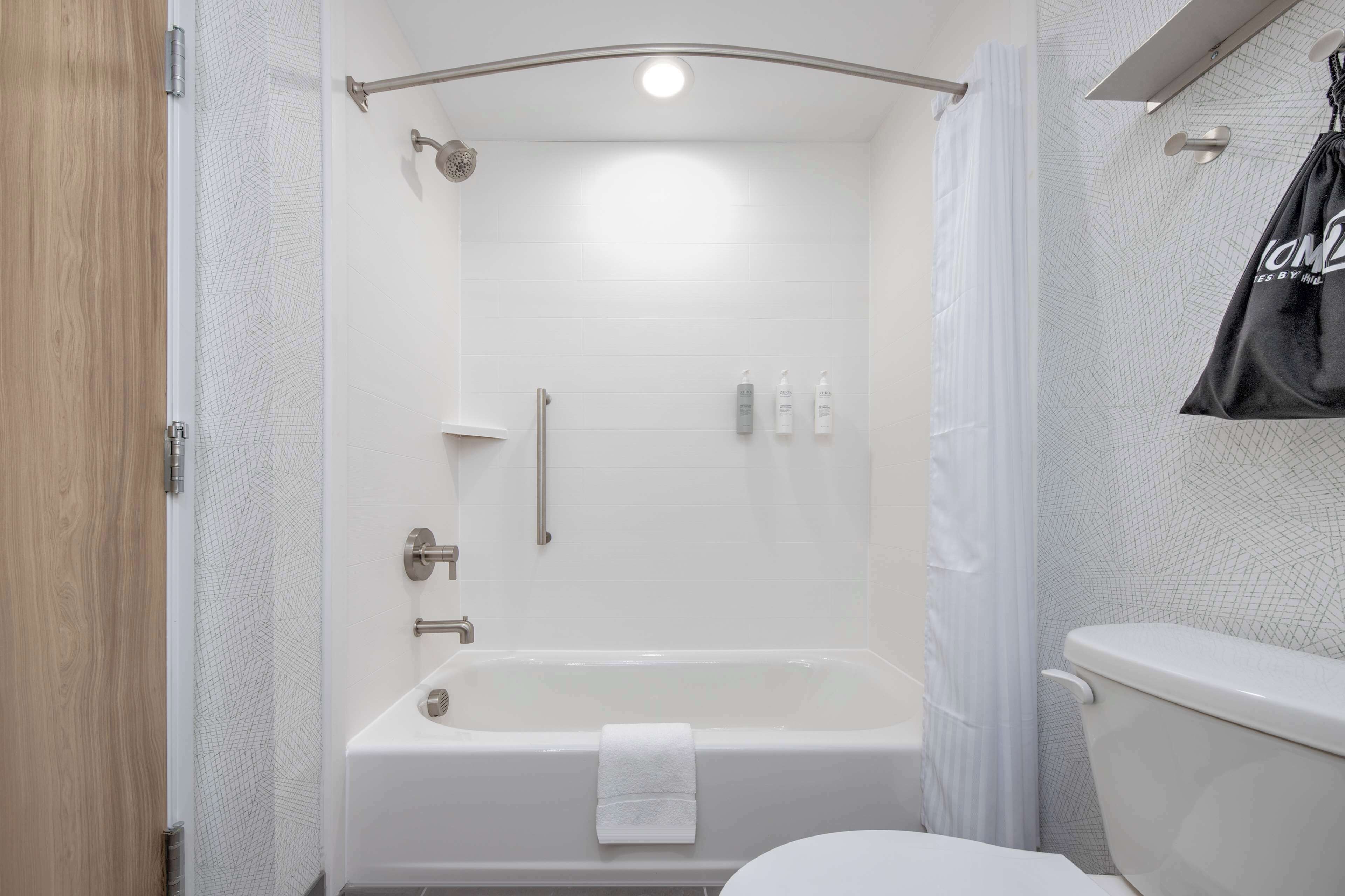 A modern bathroom with a bathtub, toilet, and shower area.