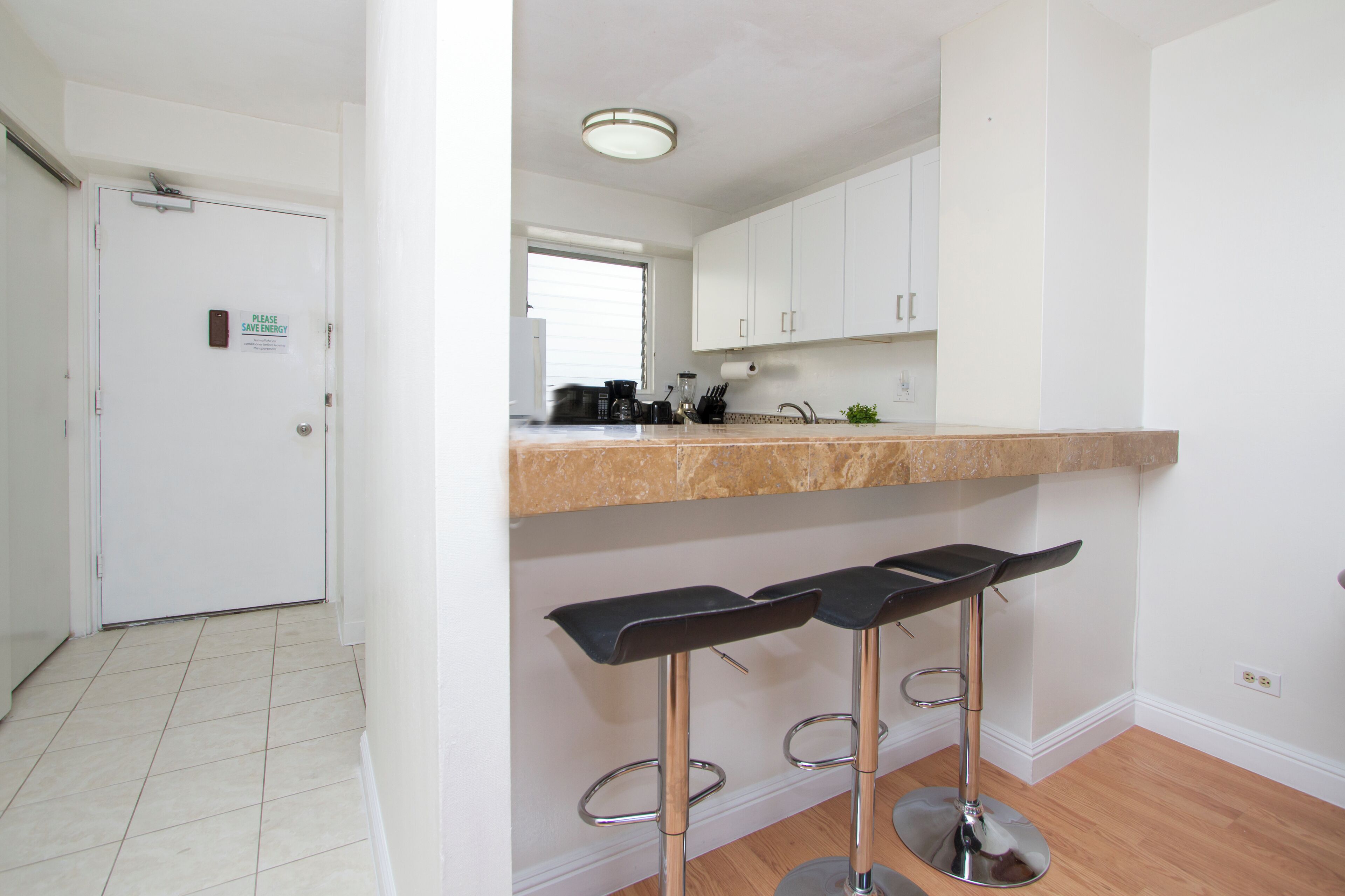 A modern kitchen with white cabinets, a countertop, and two bar stools.