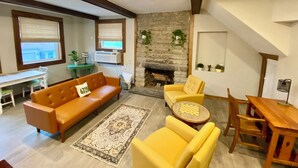 A living room with a fireplace, a sofa, a coffee table, and a dining area with chairs and a table.