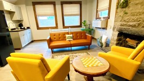 A living room with a sofa, two yellow armchairs, and a round coffee table with a chessboard.