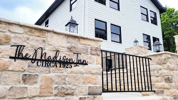 A stone wall with a metal gate and a sign that reads "The Madison Inn Circa 1925."