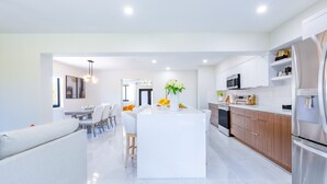 A modern kitchen with white cabinetry, a central island, and stainless steel appliances. - Welcome to Casa Luna – Your Private Oasis with Heated Pool! (Cutler Bay)