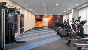 Un gimnasio con cintas de correr, bicicletas estáticas y máquinas de pesas.