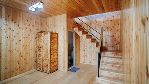 A wooden interior with a staircase, a wooden wardrobe, and a ceiling light fixture. - Bungalow (Tbilisi)