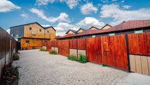 A courtyard with wooden buildings, a cobblestone path, and a clear blue sky. - Bungalow (Tbilisi)