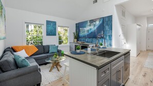 Ett modernt vardagsrum med en grå soffa, ett soffbord och ett stort fönster.