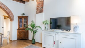 A modern living room with a TV, white cabinets, a wooden cabinet, and a potted plant. - Paolino View Apartment (Lucca)