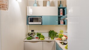 A modern kitchen with a microwave, fresh produce, and decorative items on shelves. - Paolino View Apartment (Lucca)